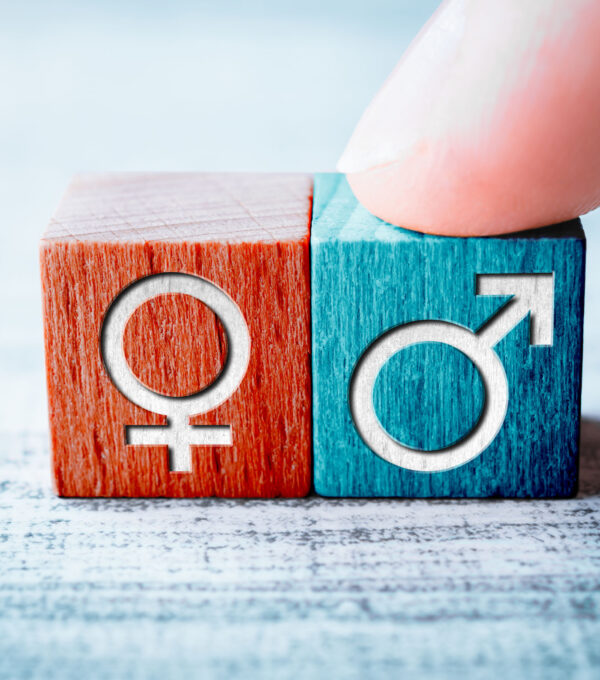 Gender Icon For Male On A Wooden Block Arranged By One Finger Next To The Female Sign On A Table